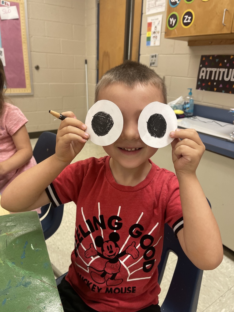 student holding up large frog eyes